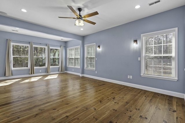 empty room featuring visible vents, a healthy amount of sunlight, baseboards, and wood-type flooring