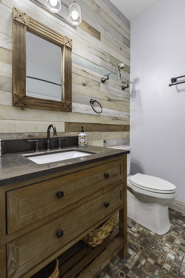 bathroom with vanity, toilet, and wood walls