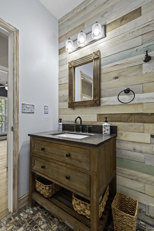 bathroom featuring wood walls, vanity, and a ceiling fan