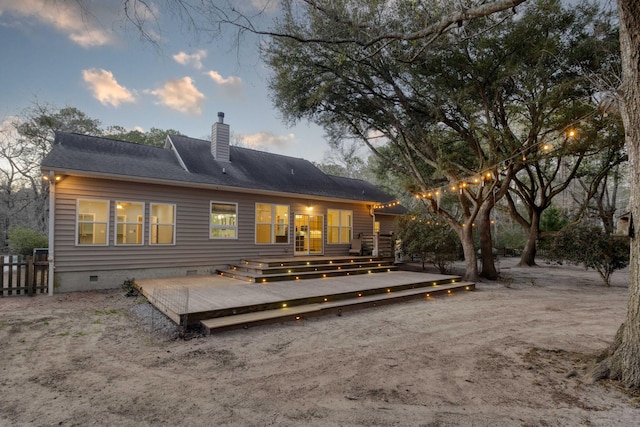 back of property at dusk featuring a deck, fence, a chimney, and crawl space