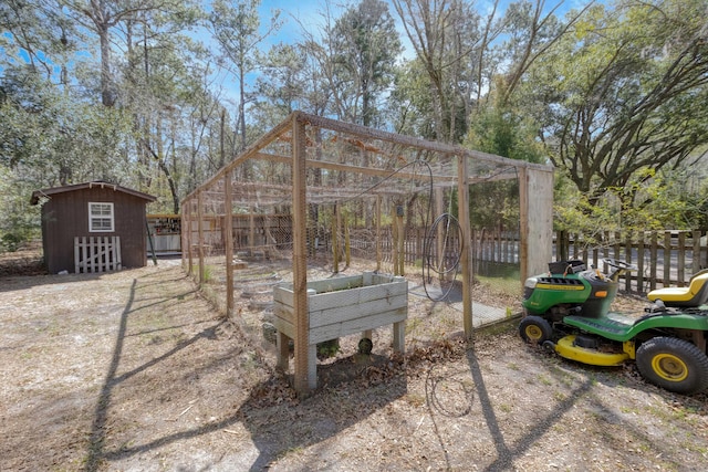 view of yard featuring a garden, a storage shed, an outdoor structure, and fence