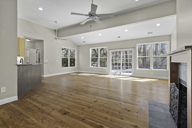 unfurnished living room featuring visible vents, vaulted ceiling, a wealth of natural light, hardwood / wood-style floors, and a fireplace