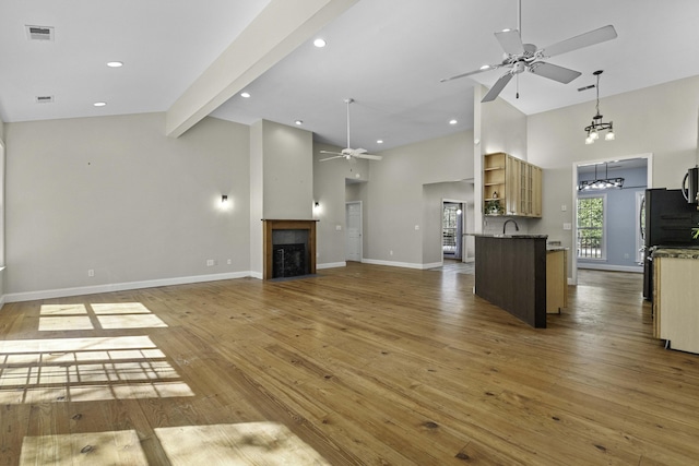 unfurnished living room with light wood-type flooring, visible vents, a fireplace, baseboards, and ceiling fan