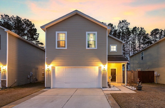 traditional home featuring concrete driveway, an attached garage, and fence