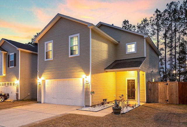 traditional home featuring a garage, concrete driveway, and fence