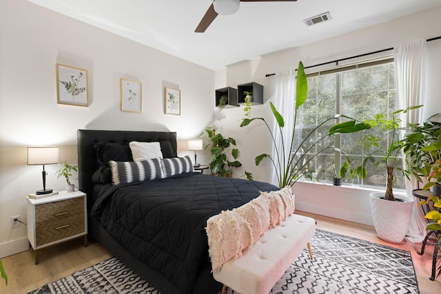 bedroom with ceiling fan, wood-type flooring, and multiple windows