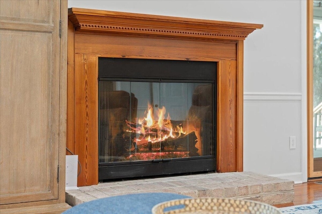 interior details featuring wood finished floors and a glass covered fireplace