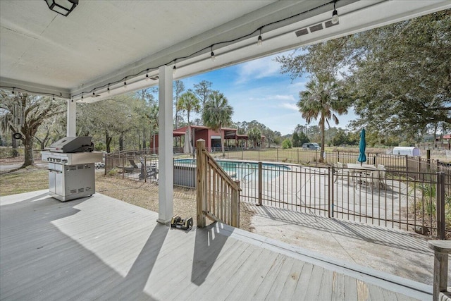 wooden deck with grilling area, fence, and a fenced in pool