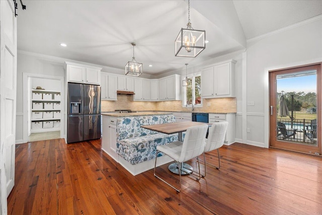 kitchen featuring under cabinet range hood, fridge with ice dispenser, ornamental molding, and white cabinets