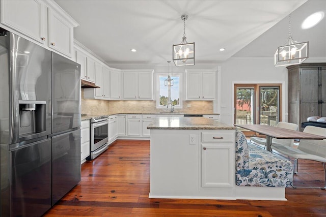 kitchen with stainless steel appliances, tasteful backsplash, an inviting chandelier, a sink, and under cabinet range hood