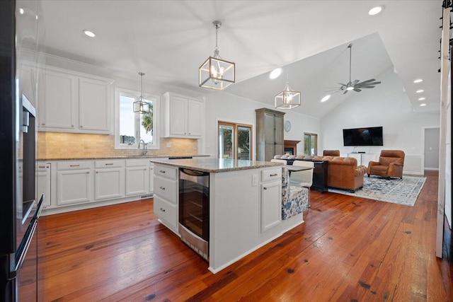 kitchen with dark wood-style floors, wine cooler, vaulted ceiling, and white cabinetry