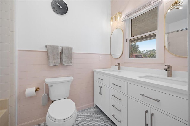 bathroom with wainscoting, a sink, tile walls, and toilet