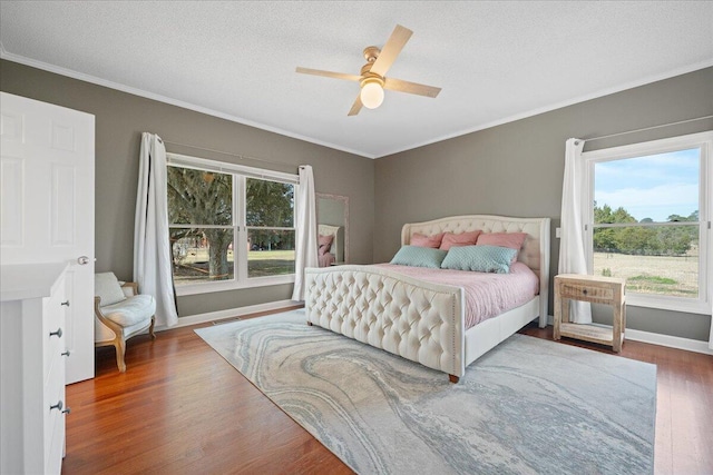 bedroom with a textured ceiling, ornamental molding, wood finished floors, and a ceiling fan