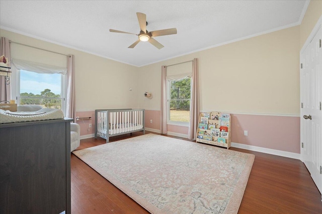 bedroom featuring crown molding, baseboards, ceiling fan, and wood finished floors