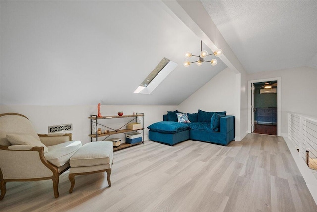 living area with a textured ceiling, vaulted ceiling with skylight, light wood-type flooring, and a notable chandelier