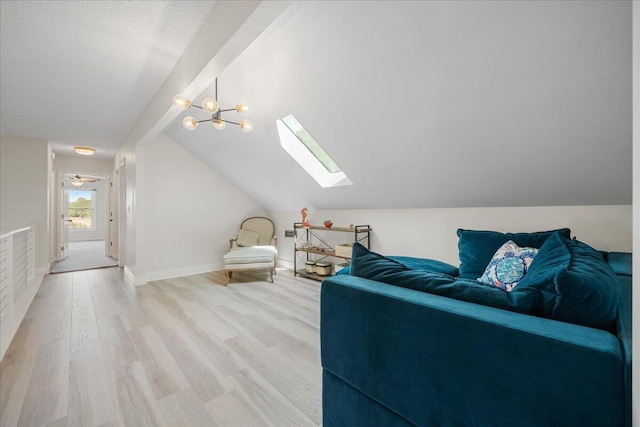 living area featuring vaulted ceiling with skylight, light wood-style flooring, and baseboards