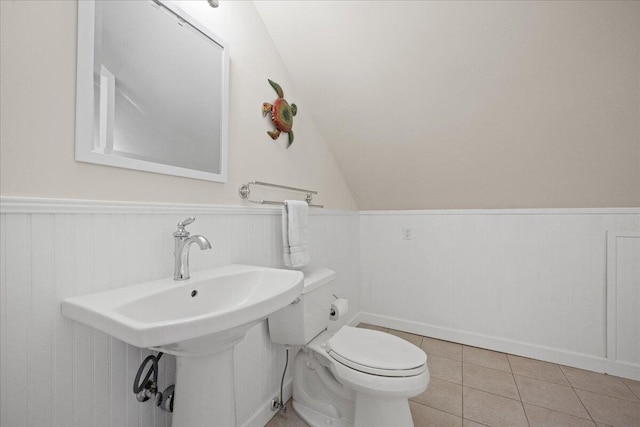 bathroom featuring a wainscoted wall, tile patterned flooring, toilet, and lofted ceiling