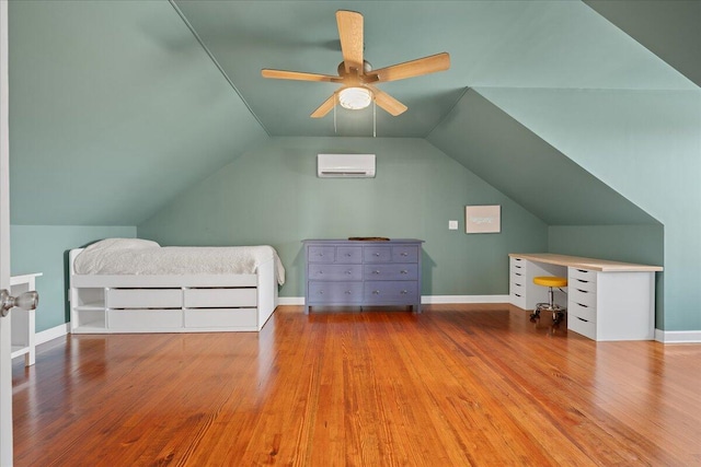 unfurnished bedroom featuring lofted ceiling, baseboards, wood finished floors, and a wall mounted AC