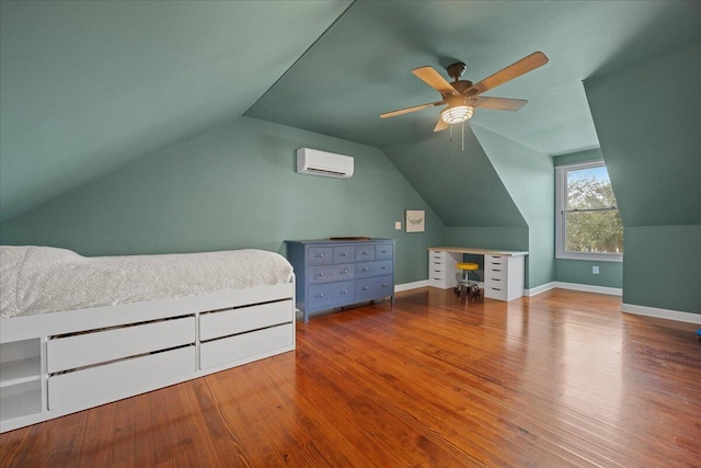 bedroom with lofted ceiling, ceiling fan, a wall unit AC, wood finished floors, and baseboards