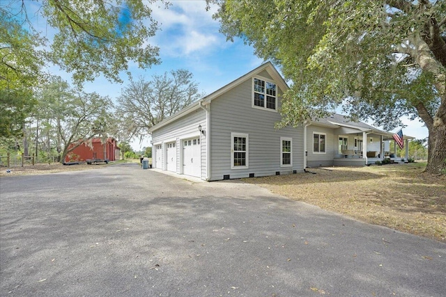 view of property exterior featuring a garage, covered porch, and driveway