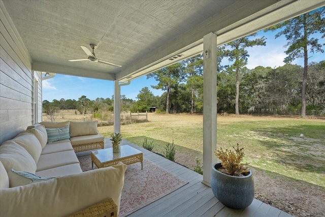 deck featuring outdoor lounge area, a ceiling fan, and a yard