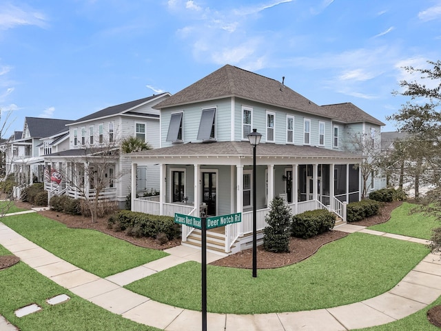 view of front of house with a front yard, covered porch, and roof with shingles