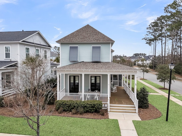 view of front of home featuring covered porch, a shingled roof, and a front lawn