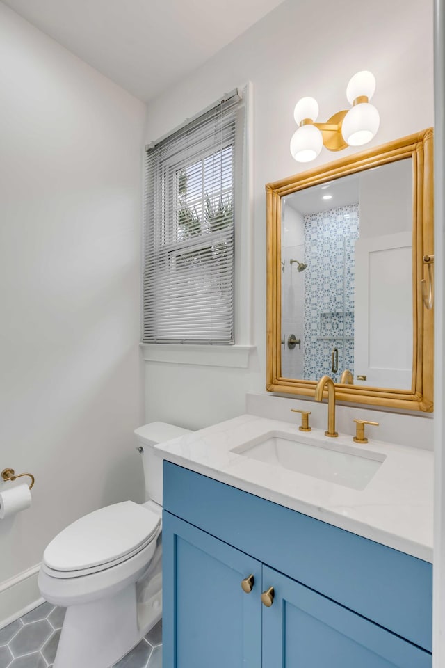 bathroom featuring vanity, a tile shower, toilet, and tile patterned flooring