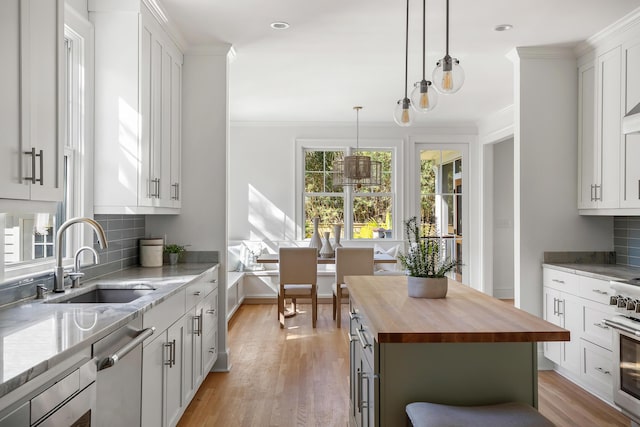 517 Royall Ave, Mount Pleasant, SC 29464 - kitchen with butcher block counters, a sink, stainless steel dishwasher, light wood-type flooring, and tasteful backsplash