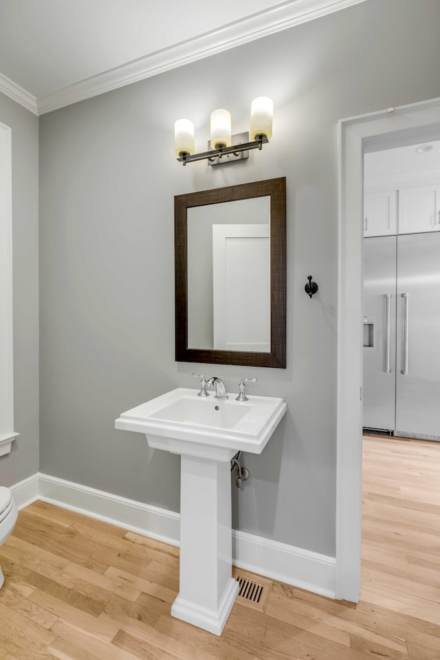 bathroom with toilet, crown molding, and wood-type flooring