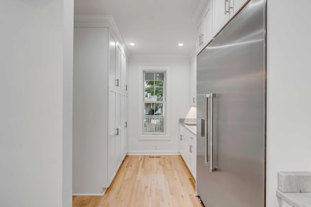 kitchen with white cabinetry, crown molding, light wood-type flooring, and high quality fridge