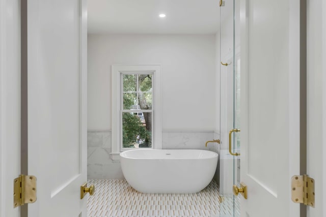 bathroom featuring tile walls, a tub to relax in, and tile patterned floors