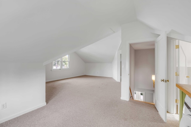 additional living space featuring vaulted ceiling and light colored carpet