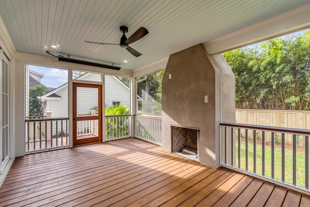 unfurnished sunroom with a large fireplace, wooden ceiling, and ceiling fan