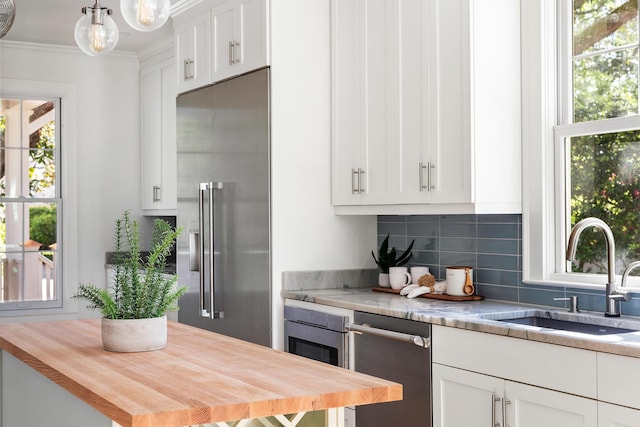 517 Royall Ave, Mount Pleasant, SC 29464 - kitchen with stainless steel appliances, a sink, backsplash, wood counters, and ornamental molding