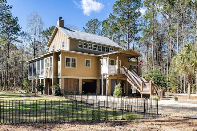 view of front facade featuring a fenced front yard, a chimney, stairs, and metal roof