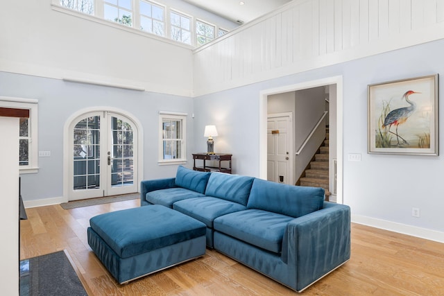 living room with baseboards, stairs, french doors, a high ceiling, and wood finished floors