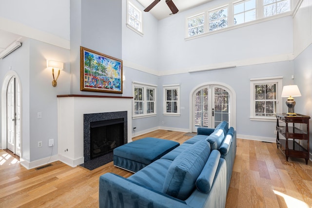 living area with a ceiling fan, wood finished floors, visible vents, and a healthy amount of sunlight