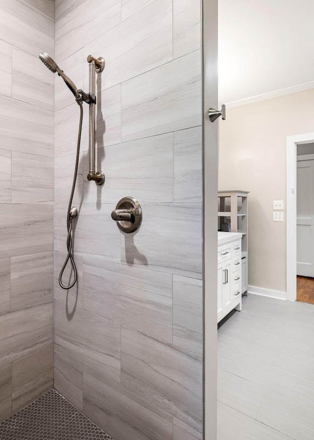 full bathroom featuring tiled shower, vanity, and baseboards