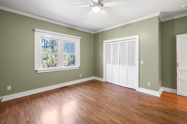 unfurnished bedroom with baseboards, wood finished floors, and crown molding