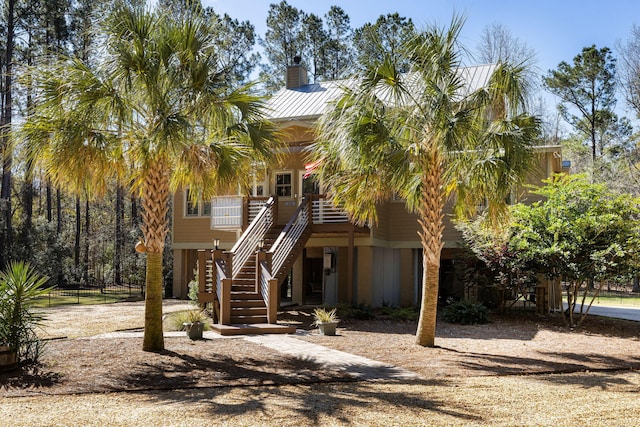 view of front facade featuring stairway, a chimney, a porch, and metal roof