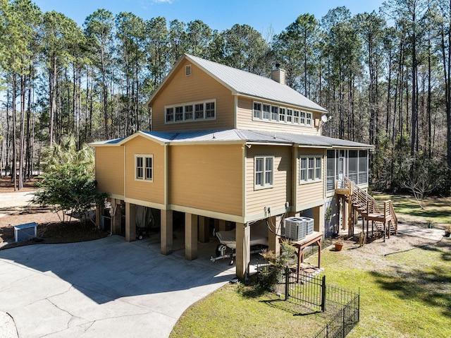 view of front of property featuring stairway, concrete driveway, a sunroom, metal roof, and a carport