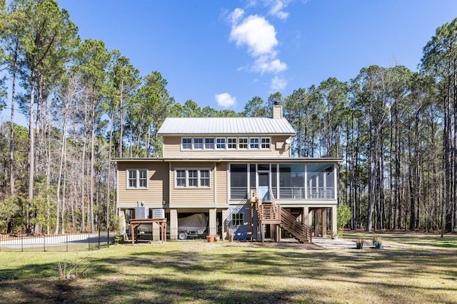 view of front facade with a front lawn, fence, stairs, a chimney, and a sunroom