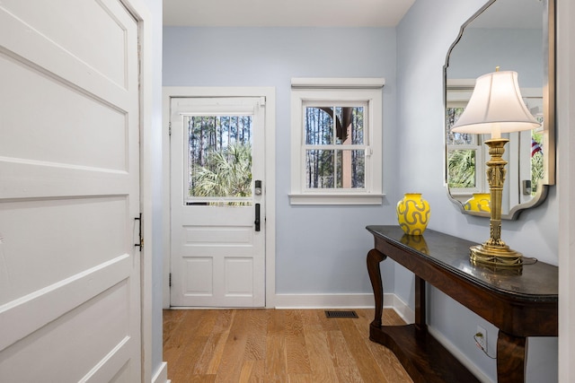 doorway to outside featuring visible vents, baseboards, and light wood finished floors