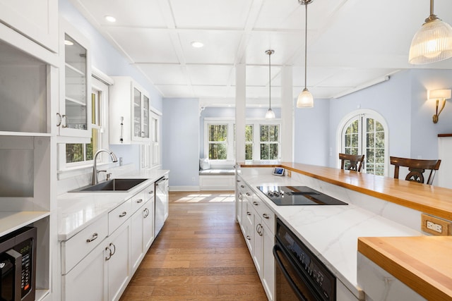 kitchen with white cabinetry, light stone countertops, stainless steel appliances, and a sink