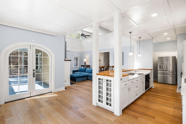 kitchen featuring cooktop, coffered ceiling, ceiling fan, and stainless steel fridge with ice dispenser