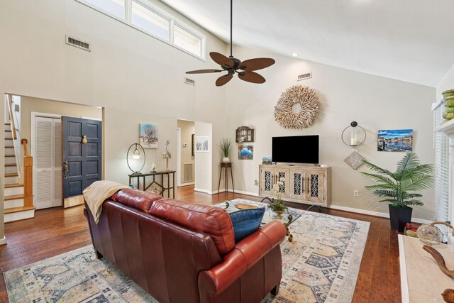 living area featuring stairway, a ceiling fan, hardwood / wood-style flooring, high vaulted ceiling, and baseboards