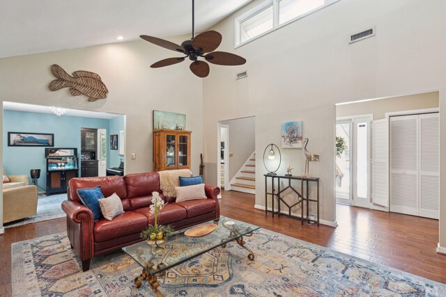 living area featuring wood-type flooring, high vaulted ceiling, a ceiling fan, stairs, and baseboards