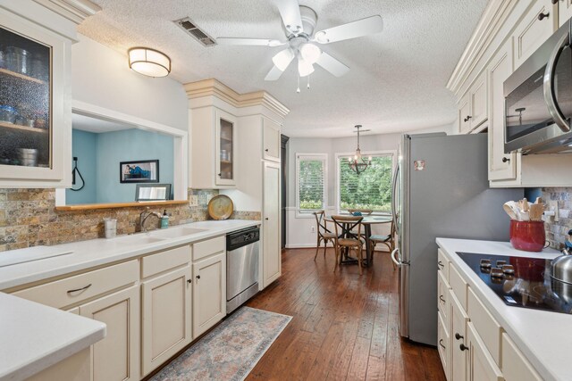 kitchen featuring stainless steel appliances, a sink, a textured ceiling, decorative backsplash, and light countertops