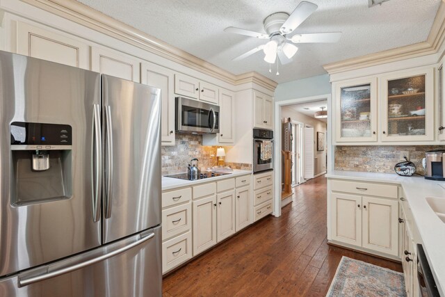 kitchen with stainless steel appliances, cream cabinetry, light countertops, ceiling fan, and decorative backsplash